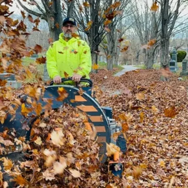 Crew member blowing fall leaves